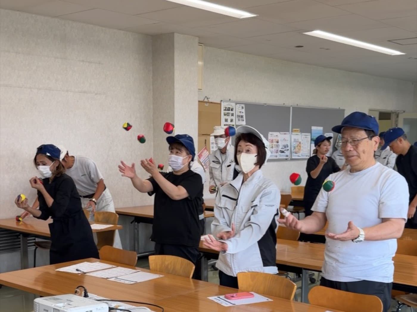 会議室で、社員がお手玉を投げ上げて受け止める課題に取り組む