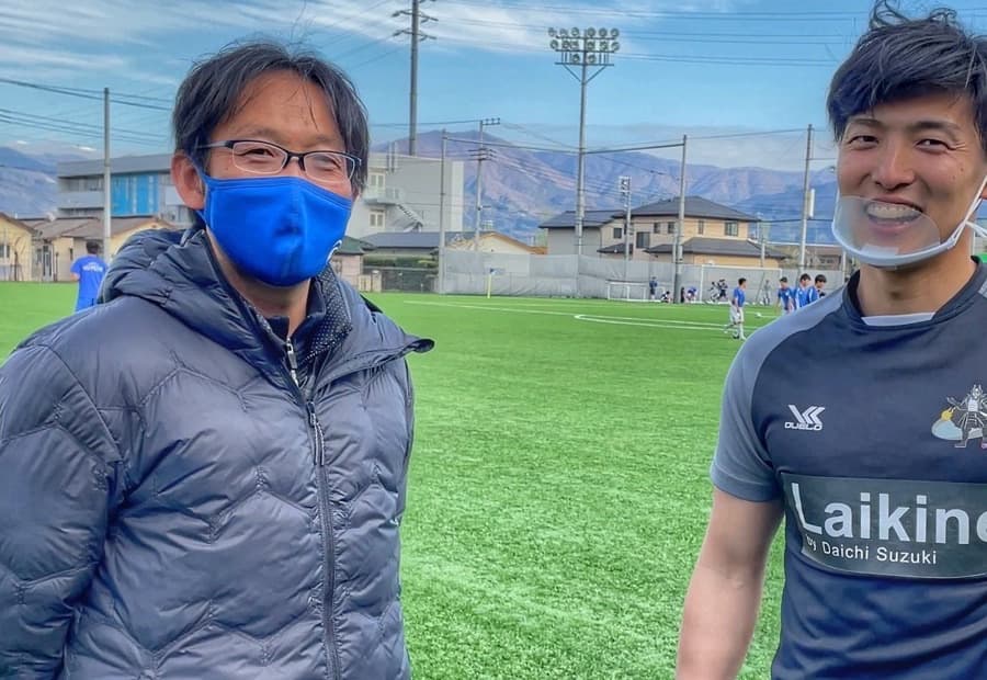 グラウンドで並ぶ山梨学院高校サッカー部 元監督とノーミングアップ代表・鈴木大地
